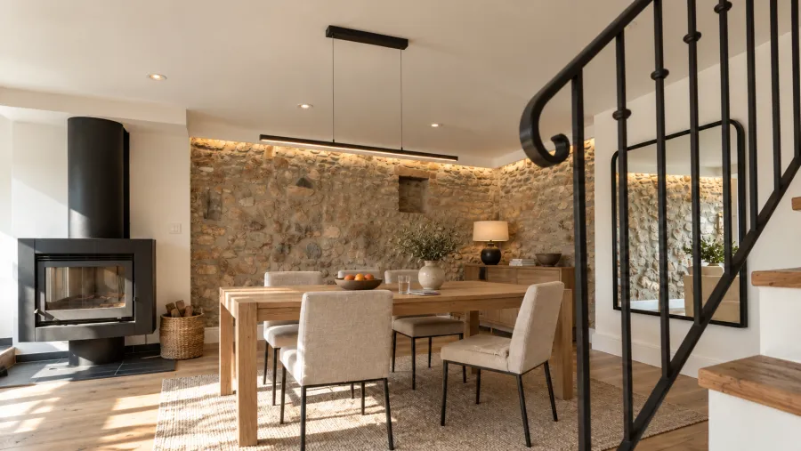Salle à manger avec poêle à bois et mur en pierre apparente