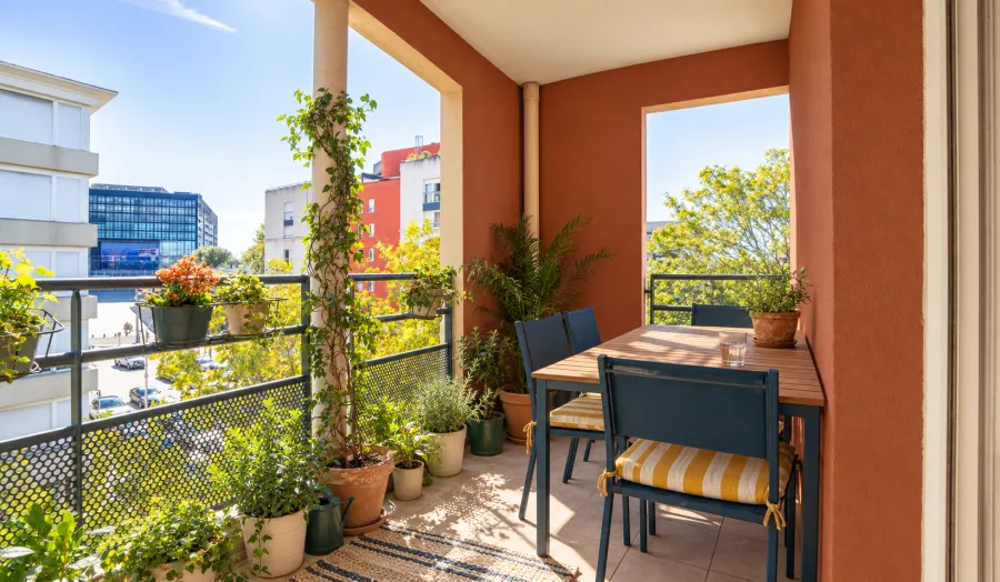 Balcon couvert avec plantes et table pour deux, vue sur la ville